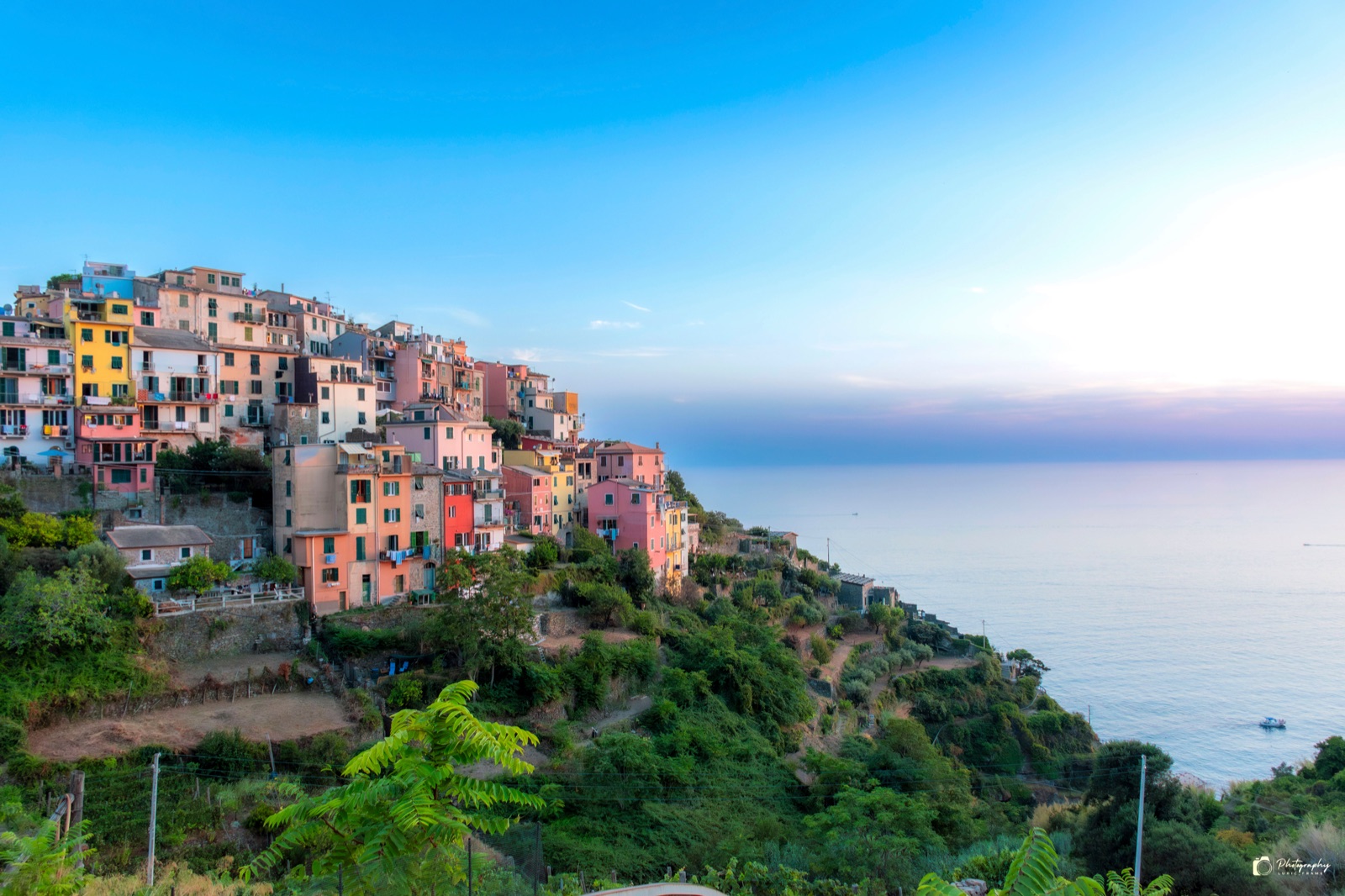Paese di case colorate sulla cima di una scogliera, nella luce chiara del tramonto sul mare